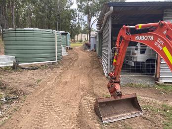 Mini excavator trenching near water tank